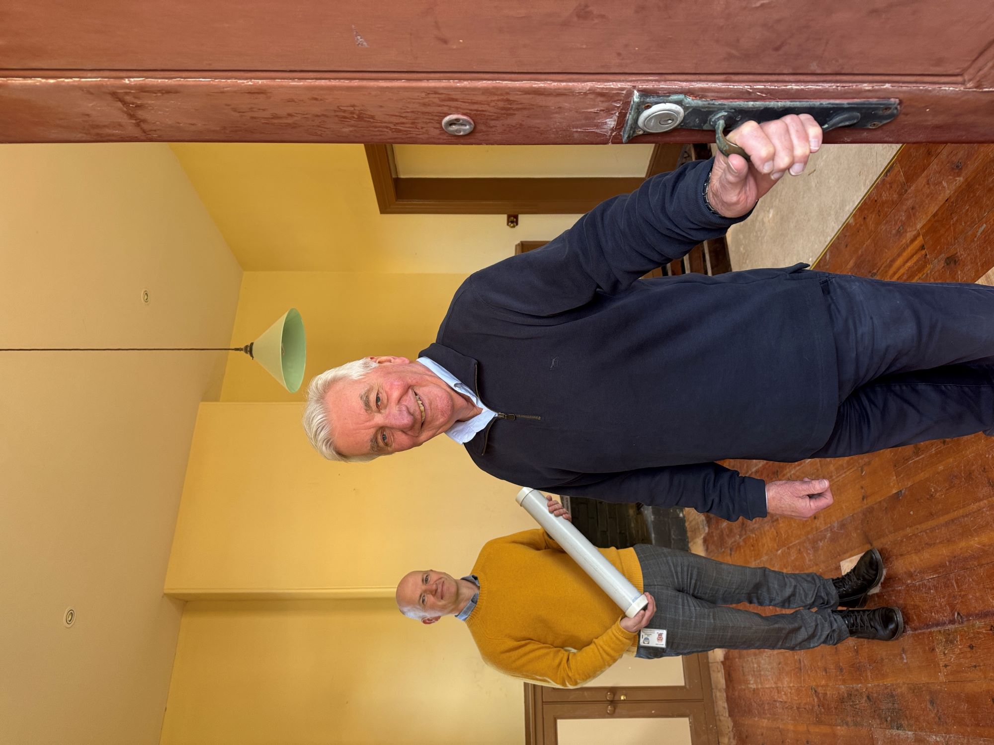Alexandrina Mayor Keith Parkes holds door of Port Elliot Council Chamber open while Council&rsquo;s Manager Projects and Design, Lee Graham, holds the poly pipe time capsule before it was returned under the floorboards.
