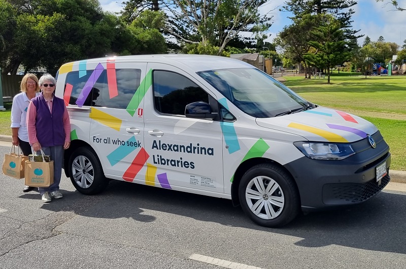 Two volunteers standing in front of the Outreach library car